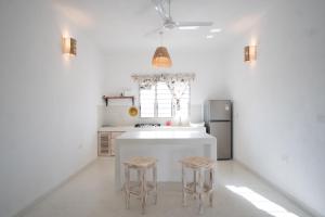 瓦塔穆Swami - Maisha Resort的厨房配有白色岛屿和2张凳子