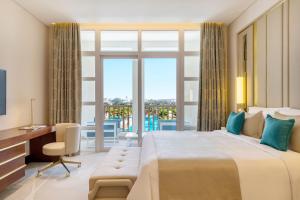 多哈Al Messila, A Luxury Collection Resort & Spa, Doha的一间卧室配有一张大床、一张书桌和一个窗户。