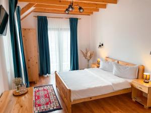 舒加塔格盐矿镇Pensiunea Ocna Maramuresului的卧室配有一张带蓝色窗帘的大型白色床