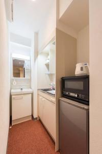 东京Serorin Light Hotel Tokyo的小厨房配有冰箱和微波炉。