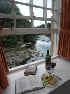 拉纳克New Lanark Self Catering Waterhouses的一张桌子,上面放着一本书,还有一杯葡萄酒和一个窗户