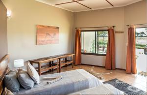 GobabisAfrica Awaits Lodge & Safaris的一间卧室配有一张床、一张桌子和一个窗户。
