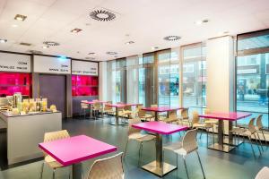不莱梅B&B Hotel Bremen-Altstadt的餐厅设有粉红色的桌椅和窗户。