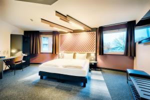 不莱梅B&B Hotel Bremen-City的卧室配有一张床、一张书桌和窗户。