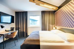 波恩B&B Hotel Bonn-West的配有一张床、一张书桌和一扇窗户的酒店客房