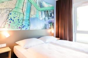开姆尼茨B&B Hotel Chemnitz的卧室配有一张床,墙上挂有绘画作品