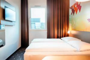库克斯港B&B Hotel Cuxhaven的配有2张床的客房设有窗户和电视。