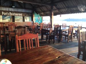 Muang KhôngPon's Riverside Guesthouse的餐厅设有木桌、椅子和桌椅