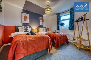 格洛斯特4 Bed Design House, 2 Off-road Parking Spaces, Great for Groups - Central Gloucester By Blue Puffin Stays的两张床位于带红色和蓝色墙壁的客房。