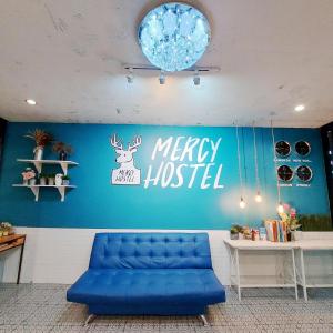 清莱Mercy Hostel的一张蓝色的沙发,房间有一个快乐的医院标志