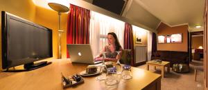 马尔什昂法梅讷卡地亚拉丁酒店的坐在酒店房间,手提电脑的女人