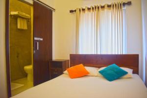科伦坡City Beds Colombo的一间卧室配有一张带两个色彩缤纷的枕头的床。
