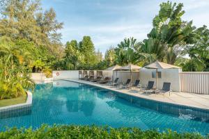 奈扬海滩Dewa Phuket Resort & Villas的一个带椅子和树木的大型游泳池