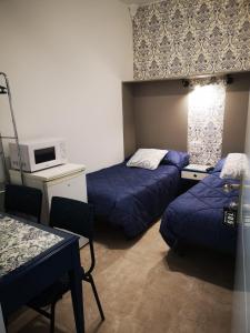 莱昂hospedaje barahona21的客房设有两张床、一张桌子和一台微波炉。