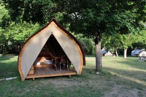 RecoubeauHabitat Créateur - Hébergements insolites au camping municipal "Les Ecureuils"的田野上的小帐篷,有树