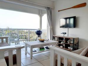 谢普斯敦港Umkhomo Place, Mangrove Beach Estate的客厅配有桌子和墙上的电视