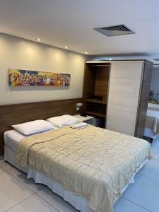 若昂佩索阿Imperial Flat Tambaú - João Pessoa的卧室配有一张大床,墙上挂有绘画作品