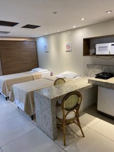 若昂佩索阿Imperial Flat Tambaú - João Pessoa的客房设有两张床、一张桌子和一台微波炉。