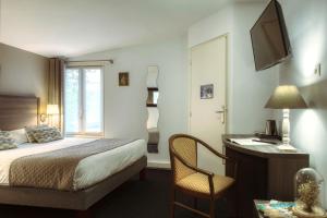 圣西尔-莱科勒圣西尔凡尔赛阿罗特尔酒店 - 寂静的舞台的酒店客房配有一张床、一张书桌和一台电视。