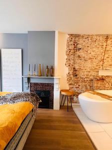 布雷达Georgia's Bathhouse的一间卧室配有一张床、一个浴缸和一个壁炉