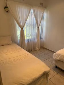 斯科特堡Mtunzi Park, 39 Peaceful shores的一间卧室设有两张床,窗户配有窗帘
