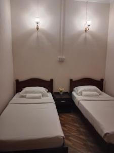 Kuala PenyuMargereth Cottage的两张床位于带两盏挂在墙上的灯的房间