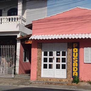 圣佩德罗-达阿尔德亚Pousada Sol de Verão的一条街道上白色门的粉红色建筑