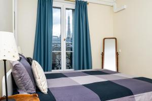 巴黎Eiffel Tower view Residence的一间卧室配有一张带蓝色窗帘的床和一扇窗户