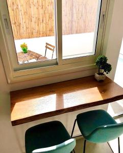 贝尔谢巴Pninat Hadrom的窗户前的一张桌子和两把绿色椅子