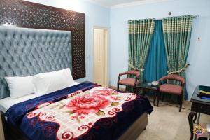 卡拉奇Capry Guest House的一间卧室配有一张带花卉床罩的床和两把椅子
