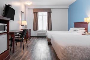 汉密尔顿Premier Inn & Suites - Downtown Hamilton的酒店客房设有两张床、一张桌子和一台电视。