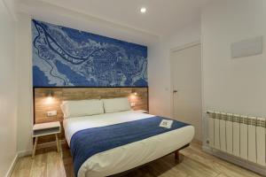 毕尔巴鄂Casual Blue的卧室配有一张大床,墙上挂有绘画作品
