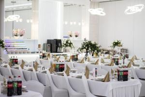 SierpcHotel Ambrozja的一间设有白色桌子和白色椅子及鲜花的房间