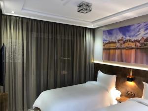 丹吉尔Hotel Appartement Tanger的一间卧室设有两张床,墙上挂着一幅画