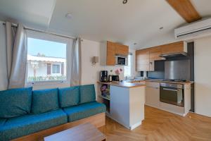 弗雷瑞斯Mobil Home Manon的一间带蓝色沙发的客厅和一间厨房