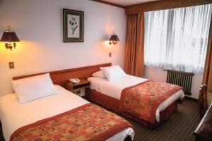 蓬塔阿雷纳斯HOTEL LOS NAVEGANTES的酒店客房设有两张床和窗户。