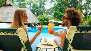 别霍港卡里布鲁海滩及丛林度假酒店的坐在桌子上喝饮料的男人和女人