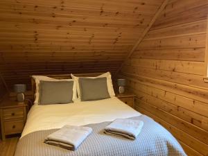 基斯Red Squirrel log cabin with hot tub的一间卧室配有一张床,上面有两条毛巾