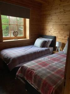 基斯Red Squirrel log cabin with hot tub的一间卧室设有两张床和窗户。
