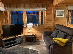 基斯Red Squirrel log cabin with hot tub的带沙发和平面电视的客厅