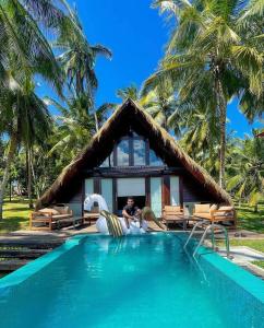 库鲁内格勒Coconut Escapes的坐在带游泳池的度假村前的人