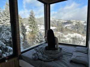 斯拉夫西克Forest Hub的坐在床上,从窗户望出去的女人