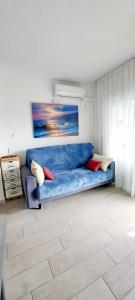 萨洛AptoVistas al mar-Font de Mar en Cap de Salou的客厅里一张蓝色的沙发,上面有绘画作品