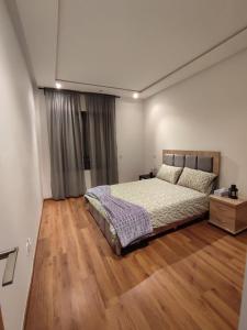DerrouaLUXURY 3 bedroom apartment with pool, Nouaceur, Morocco的一间卧室配有一张床,铺有木地板