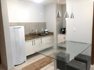 南雅拉瓜Saint Sebastian Flat 213 - Com Hidro! até 4 pessoas, Duplex, no centro的厨房配有玻璃桌和冰箱