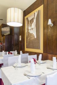 阿拉力兹阿拉里克餐厅旅馆的一间设有白色桌子和墙上照片的用餐室