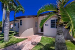 棕榈滩Villa Tamar的前面有棕榈树的房子