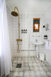 克里斯蒂娜港欧姆普拉斯加德宾馆的白色瓷砖浴室设有水槽和淋浴