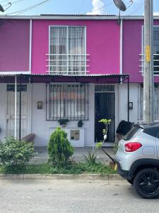 佩雷拉Casa Familiar Pereira Manzana的一座粉红色的房子,前面有一辆汽车