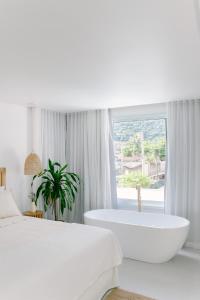马利西亚斯Olisa Hotel Boutique的一间白色卧室,配有浴缸和大窗户